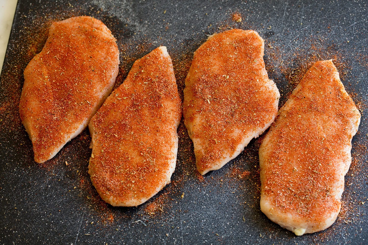 Spice seasoned chicken breasts shown before cooking.