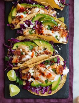 Row of fish tacos on a black slate serving platter.