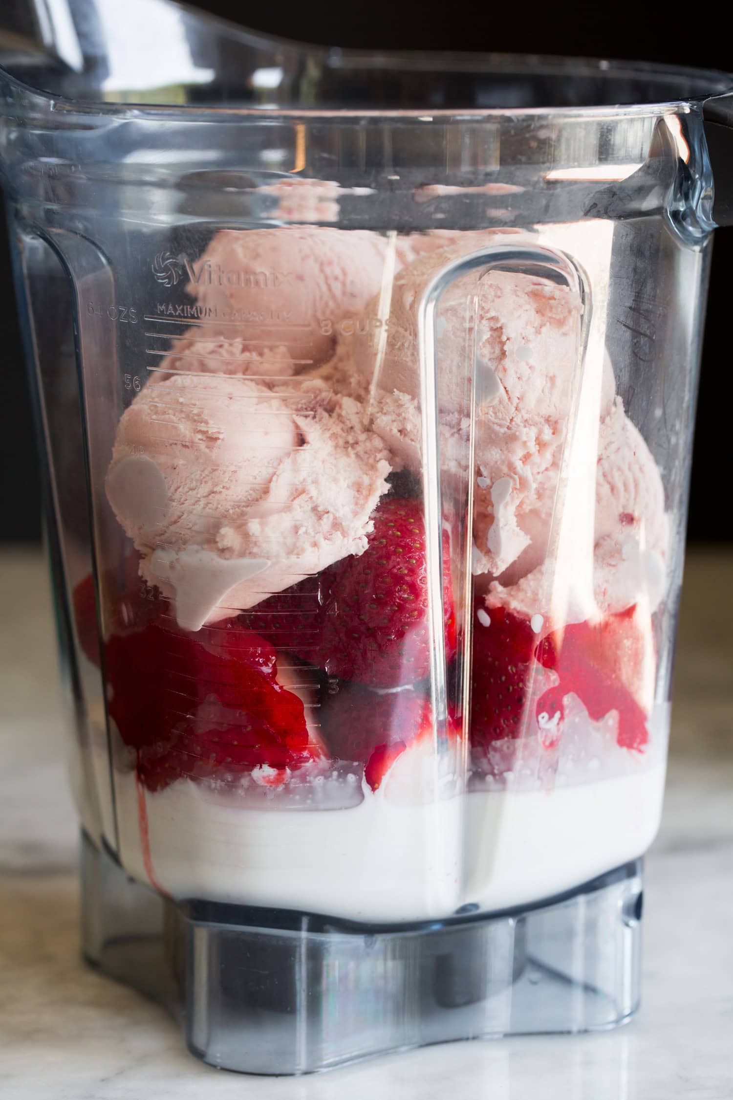 Strawberry milkshake ingredients in blender before blending.