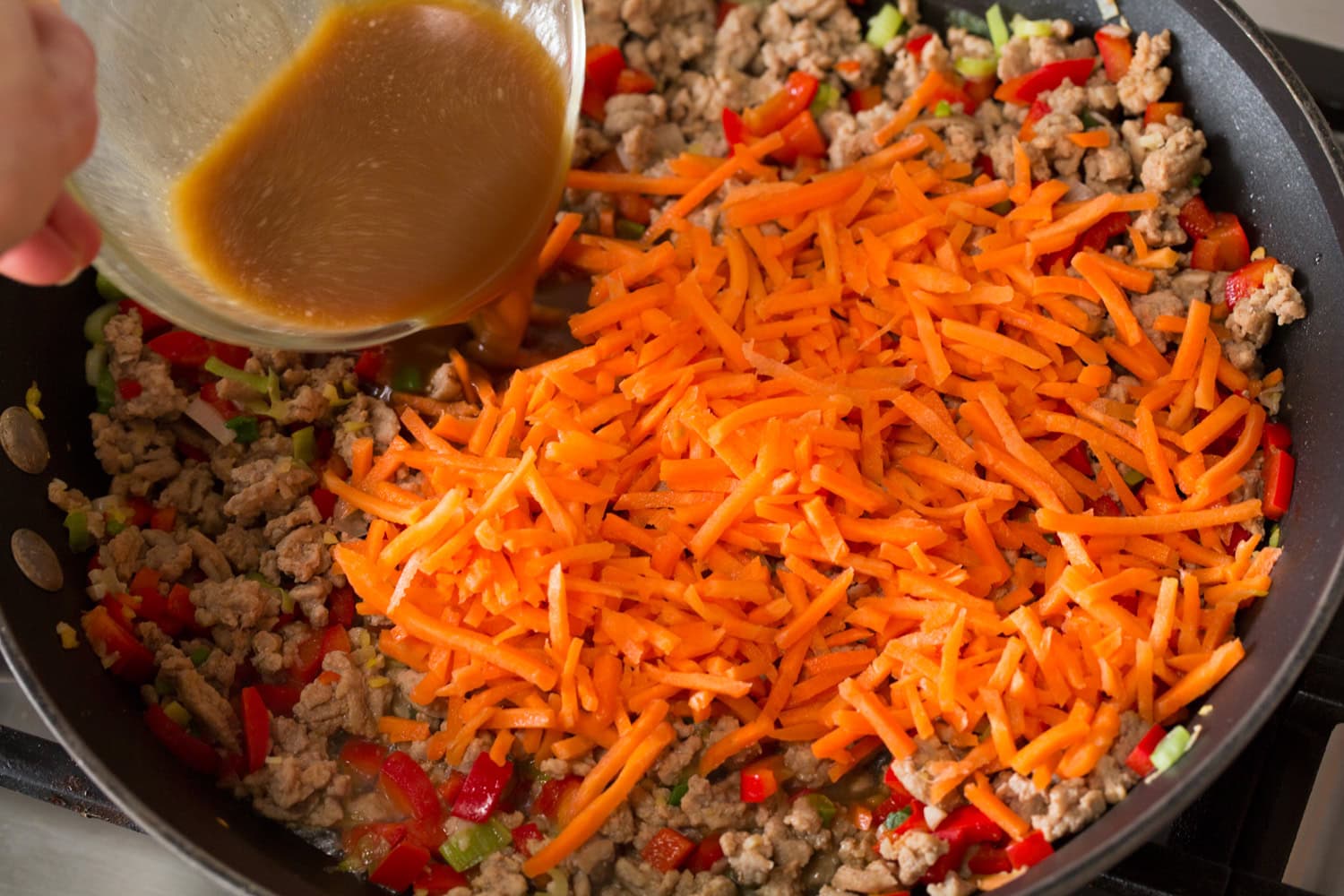 Carrots added to the ground meat mixture in the skillet.