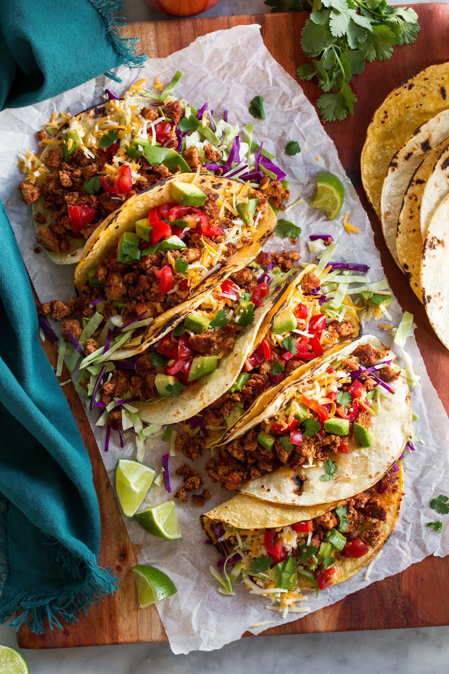 Crumbled tofu meat tacos with toppings of cabbage, tomatoes, cilantro and cheese.