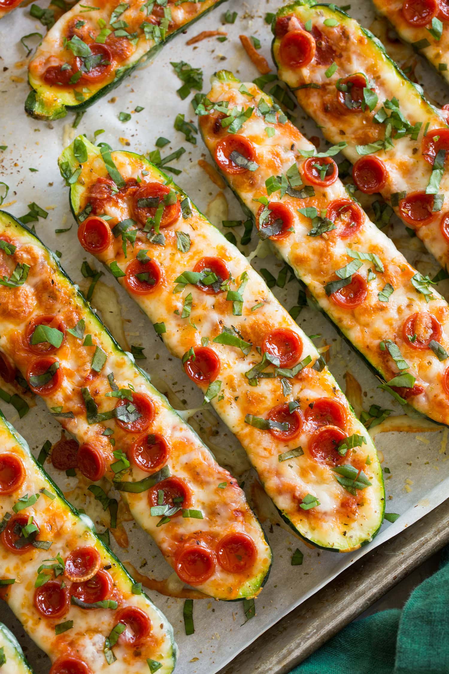 Close up photo of zucchini pizza boats on a parchment lined baking sheet. 